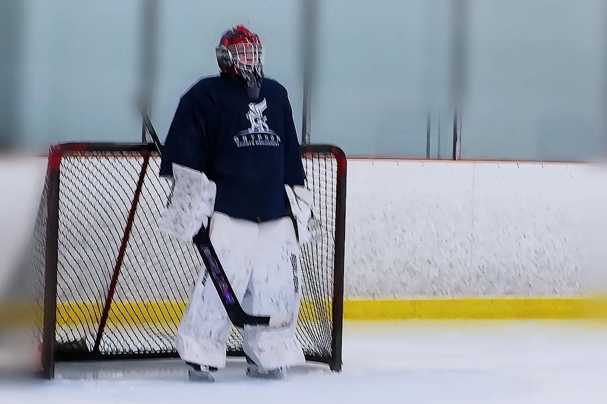 A goalie in a Gryphon Sports Management jersey standing beside the net